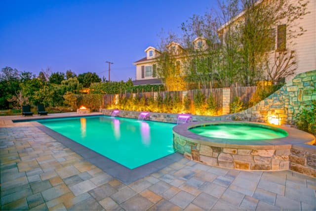 Rectangular pool with circular spa, slide, and stonework