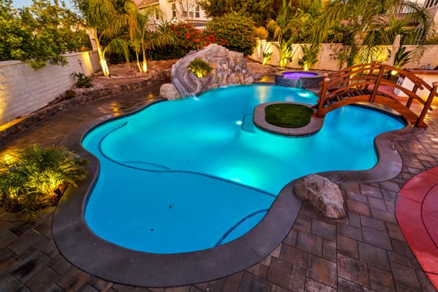 Freeform pool with natural stone grotto and spa at dusk
