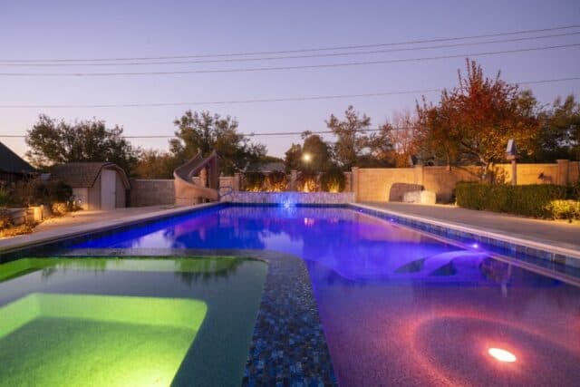 Pool and raised spa glowing under violet LED lighting